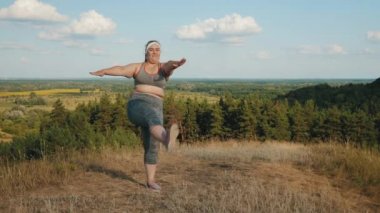 Artı boyutu kız dağlık çim üzerinde spor egzersizleri yapıyor