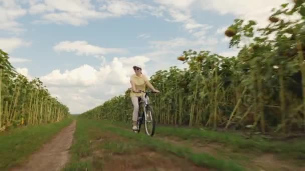 Счастливая женщина ездит на велосипеде на скорости по проселочной дороге — стоковое видео