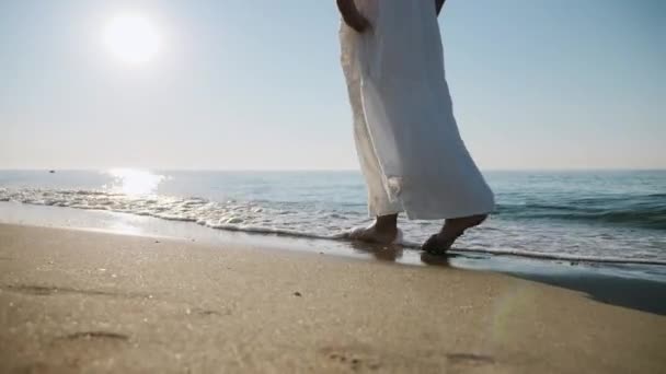 Menina em vestido branco andando descalço nas ondas do mar na costa — Vídeo de Stock