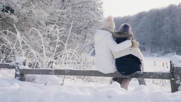 Mamá e hija abrazándose admirando el paisaje invernal — Vídeo de stock