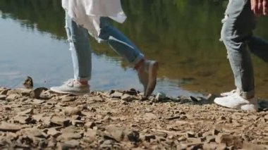 İki yürüyüşçü gölün kayalık kıyısı boyunca yürüyor.