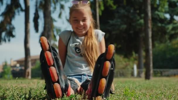 Jovencita sentada en la hierba admirando los patines — Vídeo de stock