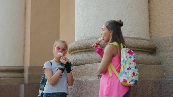 Twee vriendinnen eten van ijs en chatten in stad — Stockvideo