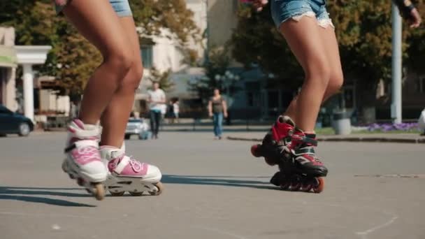 Две молодые девушки катаются на роликах на площади в городе — стоковое видео
