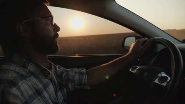 Um homem monta seu carro no fundo do pôr-do-sol — Vídeo de Stock