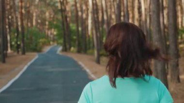 Geri görünüm: kız bir çam ormanında yol boyunca çalışır. Close