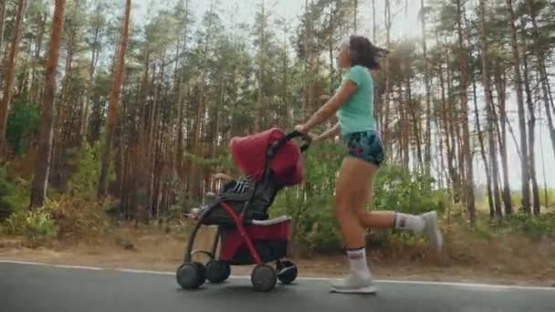 Τρέξιμο γυναίκα με καροτσάκι μωρού στο δρόμο στο δάσος — Αρχείο Βίντεο