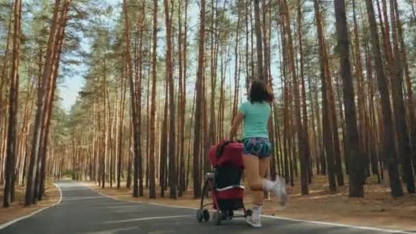 Donna in corsa con passeggino sulla strada nel bosco — Video Stock