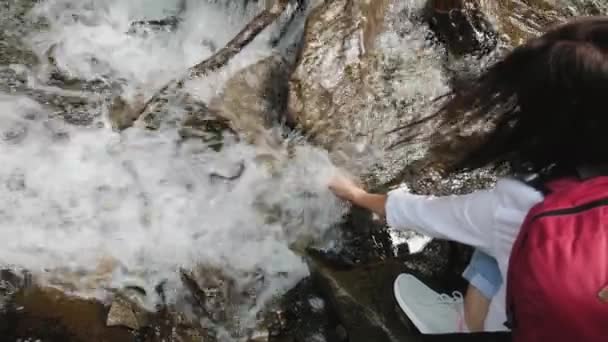 Femme touche le ruisseau d'eau de la rivière montante, boit de l'eau — Video