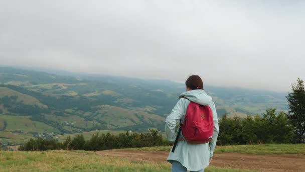 Dame randonneur avec sac à dos donnant sur les collines et les montagnes — Video