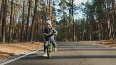 Küçük bir çocuk dengeli bisiklete biniyor, yaklaşıyor.