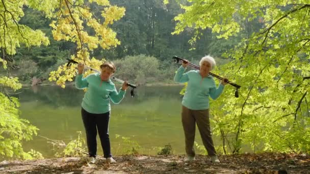 Duas mulheres idosas se aquecem antes da caminhada nórdica — Vídeo de Stock