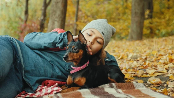 Chica se relaja en el bosque de otoño con su pinscher en miniatura — Foto de Stock