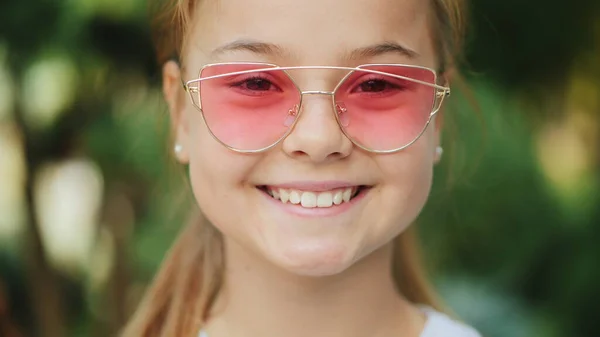 Ung leende flicka i rosa solglasögon utomhus, närbild — Stockfoto