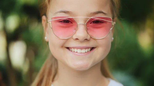 Pembe güneş gözlüğü açık havada genç gülümseyen kız, closeup
