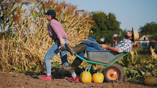 Woman takes away a wheelbarrow with a resting farmer — Stock Photo, Image