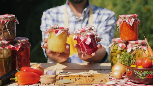 Canned vegetables in glass jars in the hands