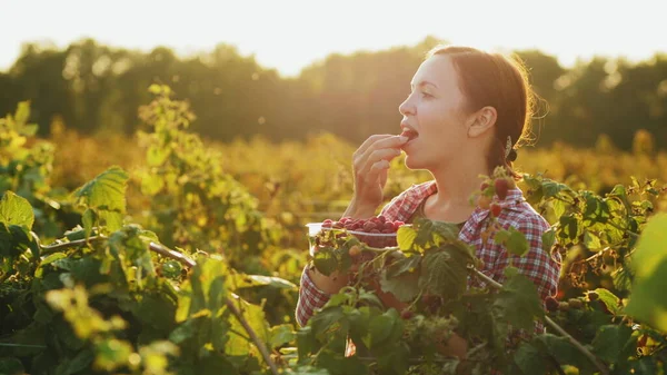 Ung kvinna äter färska, röda hallon — Stockfoto