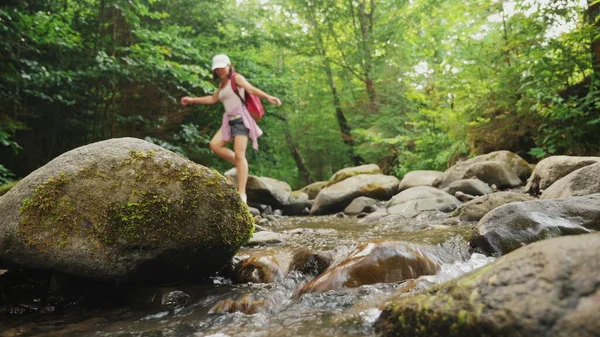 stock image A girl walks on stones along a mountain river