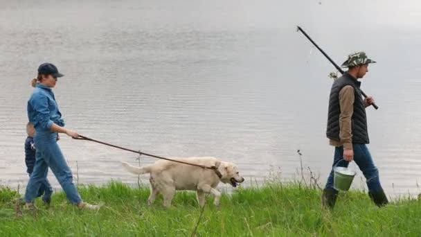 Family with a dog on vacation go fishing near the lake — Stock Video