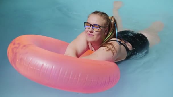 Fet kvinna simmar i en pool med en simring — Stockvideo
