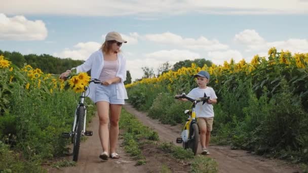 Máma a syn kráčí po venkovské silnici s jízdními koly — Stock video
