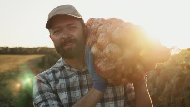 Задоволений фермер несе сумку з цибулею на плечі — стокове відео