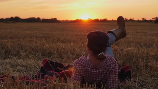 Agricoltore che riposa sulla paglia in un campo al tramonto — Video Stock