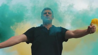 Sarı ve mavi renkli sis bombası olan adam.