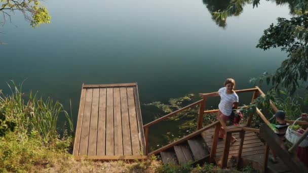 Famille jusqu'à une jetée en bois pour un pique-nique — Video