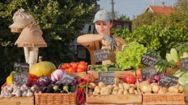 Çiftçi bir kız organik sebzeleri kese kağıdına koyar.