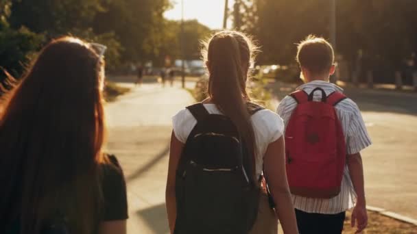Elever med ryggsäckar som går längs gatan på morgonen — Stockvideo