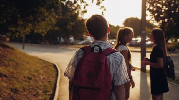 Een jongen met een rugzak loopt de straat op bij zonsopgang. — Stockvideo