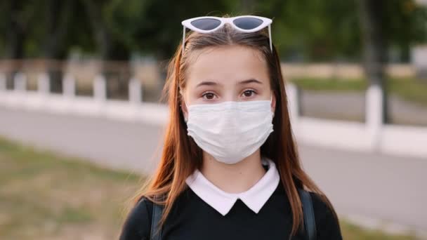 Portrait of teenage girl wearing medical mask in city park — Stock Video
