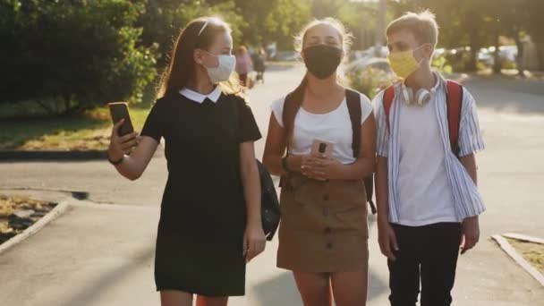 ３人の学齢の友達が通りを歩いている。 — ストック動画