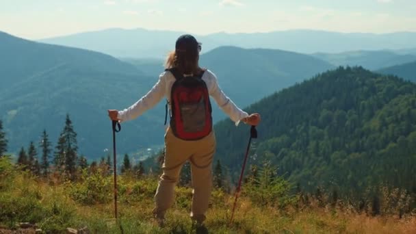 Mädchen mit Trekkingstöcken steht auf dem Gipfel des Berges — Stockvideo