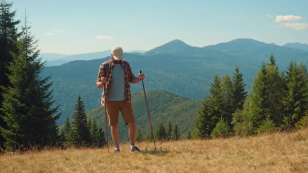 Een man met wandelstokken wandelend in de bergen — Stockvideo