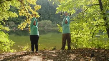 İki yaşlı kadın İskandinav yürüyüşünden önce ısınıyor