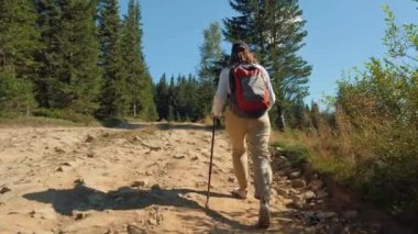 Yürüyüş direkli kadın yürüyüşçü dağlara tırmanıyor.