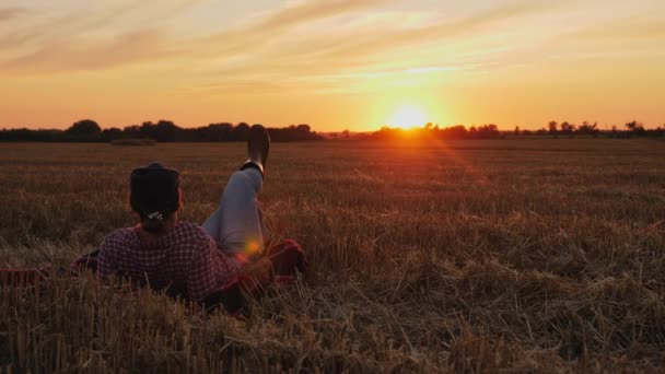 Női farmer szalmán pihen egy mezőn naplementekor. — Stock videók
