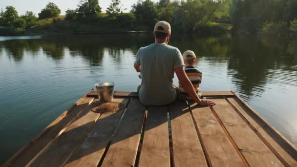 Apa és a kisfia horgásznak a tavon. — Stock videók