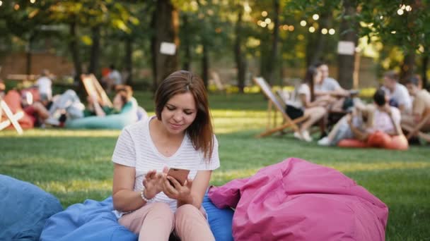 Молода жінка використовує смартфон у міському парку — стокове відео