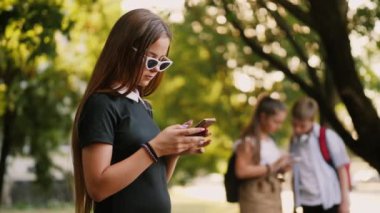 Kız parkta akıllı telefon kullanıyor.
