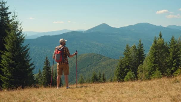 Un hombre con bastones de trekking caminando por las montañas — Vídeo de stock