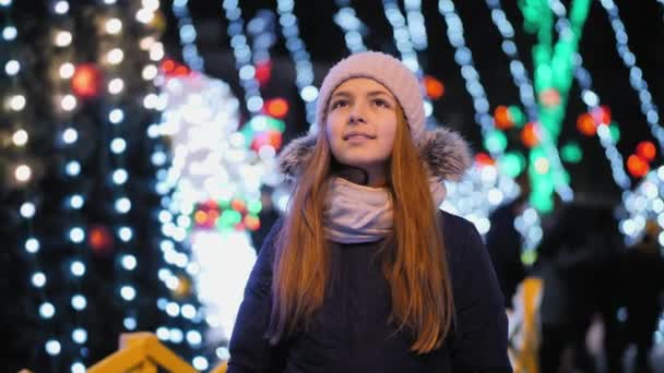 Junges Mädchen schaut auf der Straße zur Weihnachtsbeleuchtung auf — Stockvideo