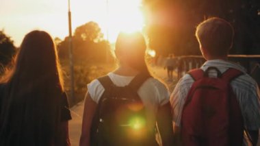 Sınıf arkadaşları gün doğumunda sokakta yürüyorlar.