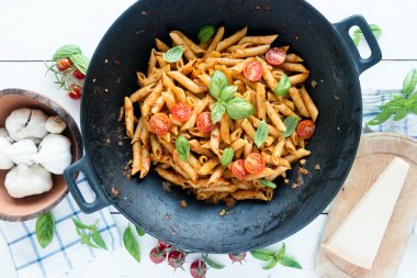 Ahşap beyaz masa üzerinde Fesleğenli domates soslu penne makarna