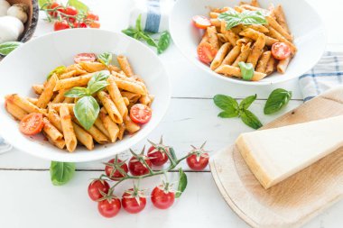 Ahşap beyaz masa üzerinde Fesleğenli domates soslu penne makarna