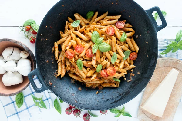 Ahşap beyaz masa üzerinde Fesleğenli domates soslu penne makarna