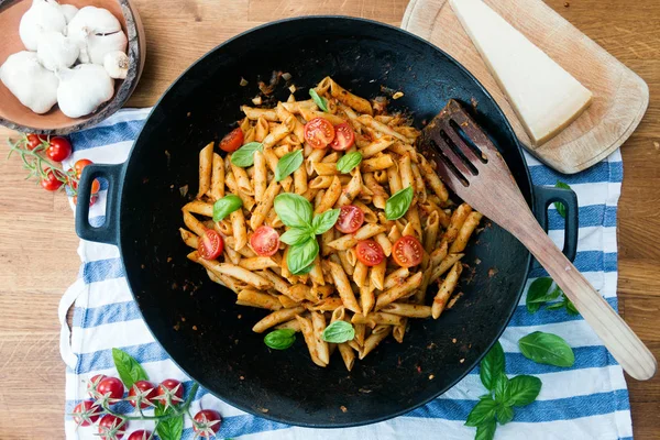 Ahşap masa üzerinde Fesleğenli domates soslu penne makarna
